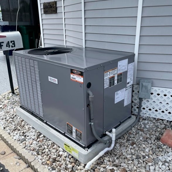 Two outdoor central air conditioning units installed on concrete pads next to a building, ready for operation.